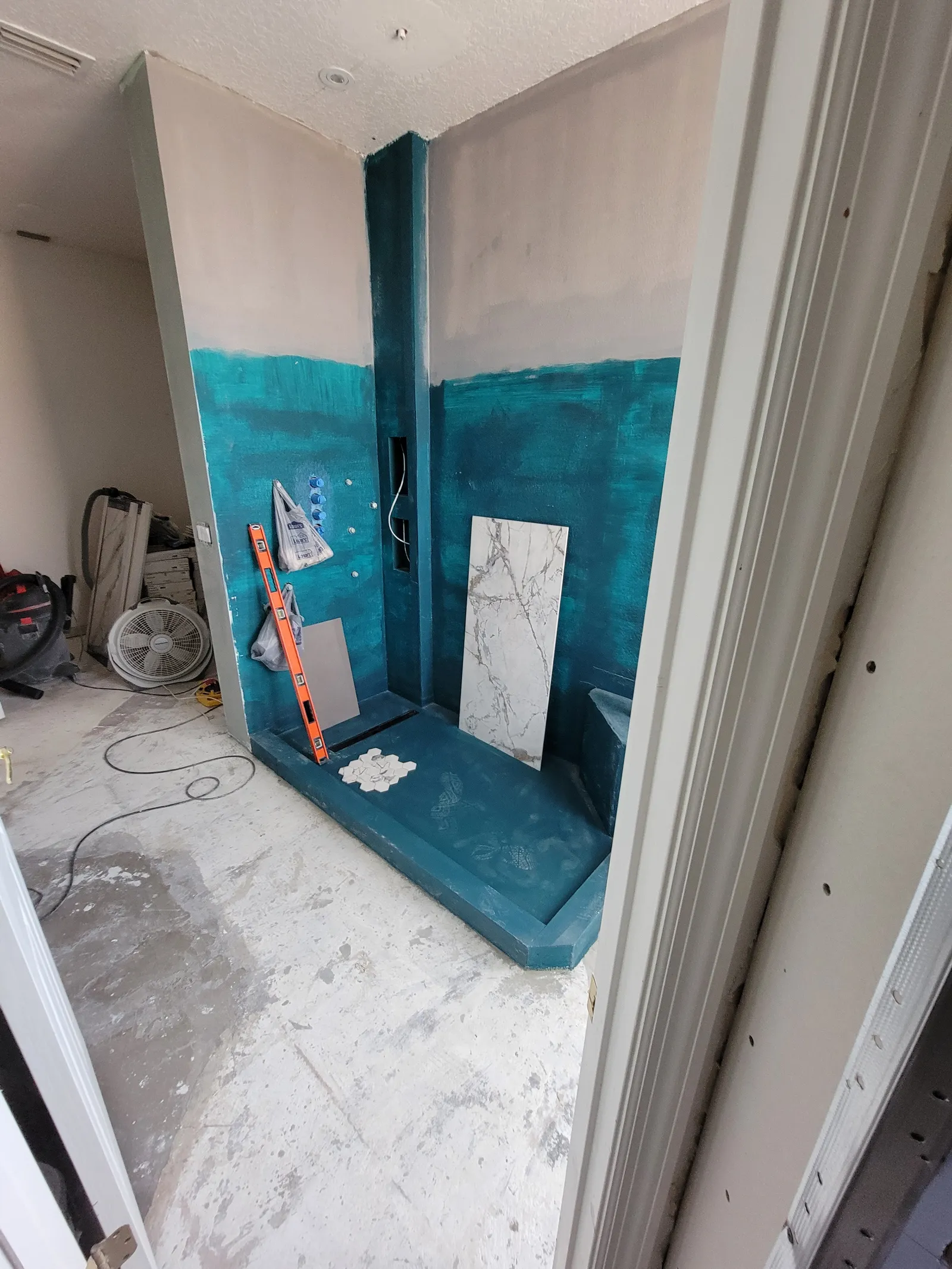 Shower walls and bench coated in teal waterproofing membrane before tile