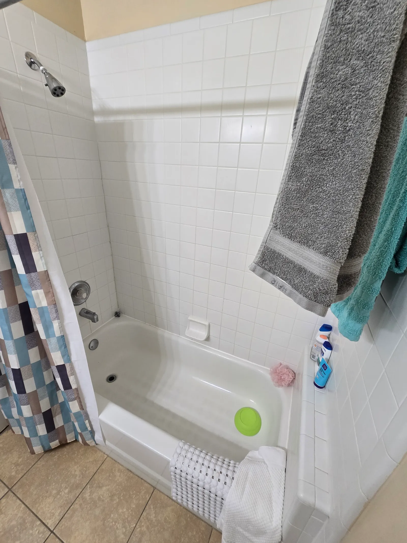 Original guest bathtub with white tile surround and shower curtain before the conversion