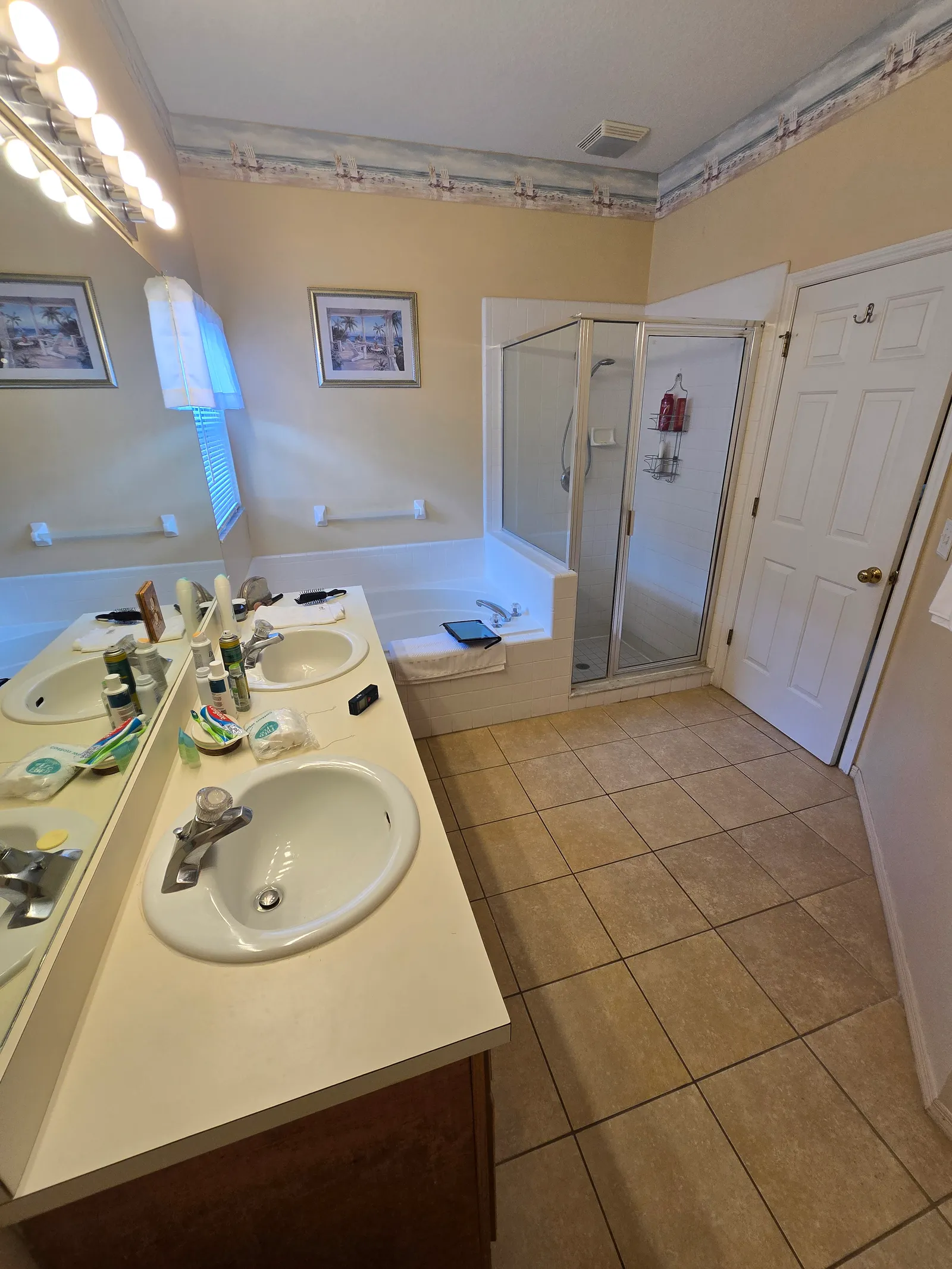 Dated master bath with corner jetted tub, framed glass shower and beige tile before the remodel