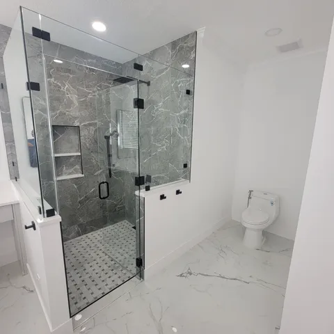 Master bath with marble-look shower, frameless glass and white vanity