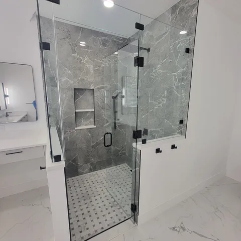 Marble-look shower with niche, black fixtures and glass door