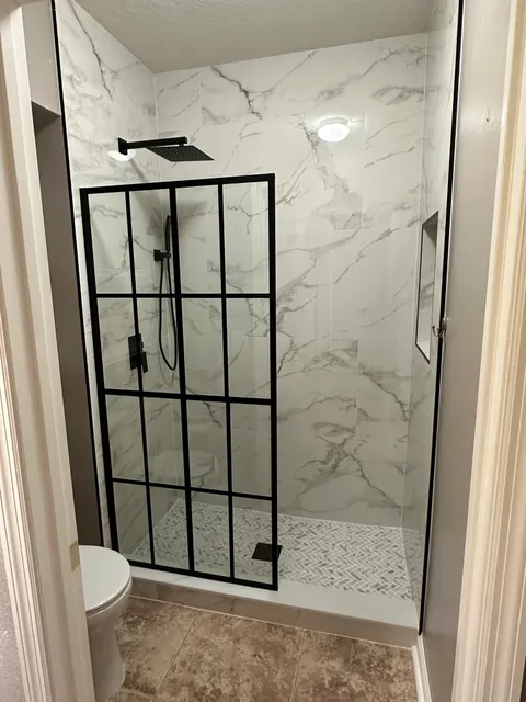 Black-frame grid glass panel on a marble-look shower