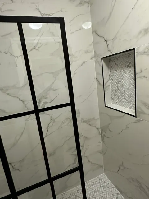 Marble-look shower with black-frame glass and mosaic floor