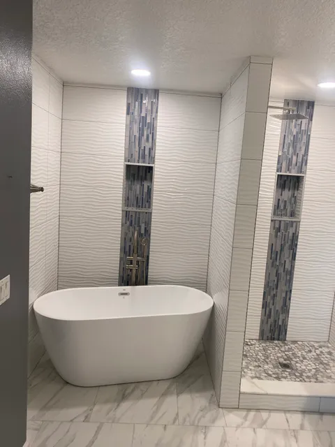 Freestanding tub and white wave tile wall