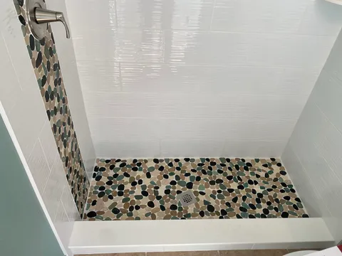 Pebble shower floor with white subway walls