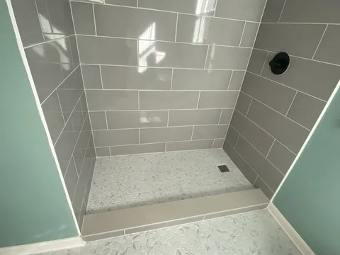Grey subway tile shower with black fixtures