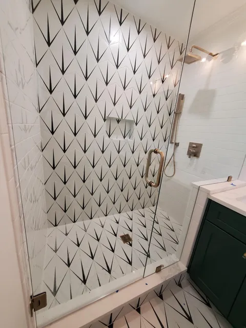 Black and white arrow patterned tile shower with gold fixtures