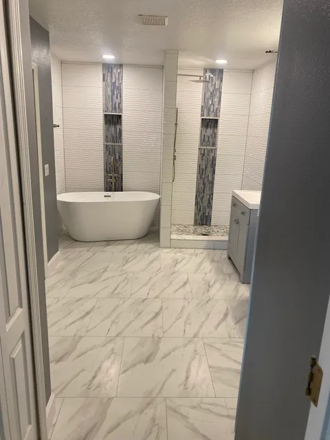 Freestanding tub and glass shower with vertical mosaic bands