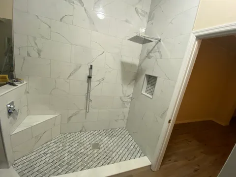 Marble-look shower with mosaic floor and wood-look bathroom floor