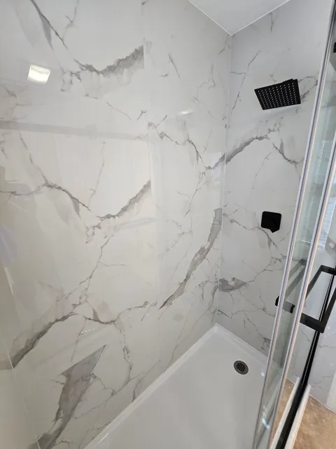 Marble-look shower with black rainhead and glass door