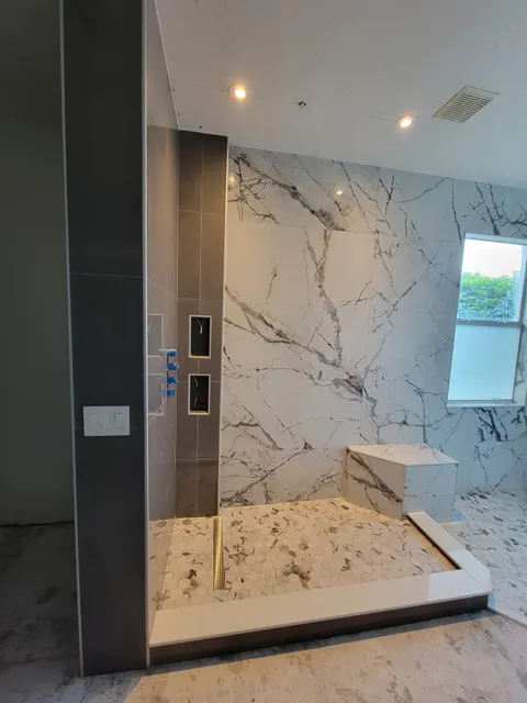Shower with marble-look walls, charcoal accent and bench