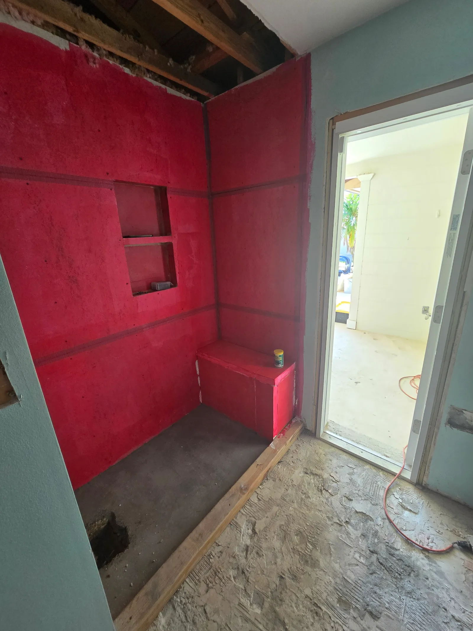 Shower walls in red waterproofing membrane with a niche framed in