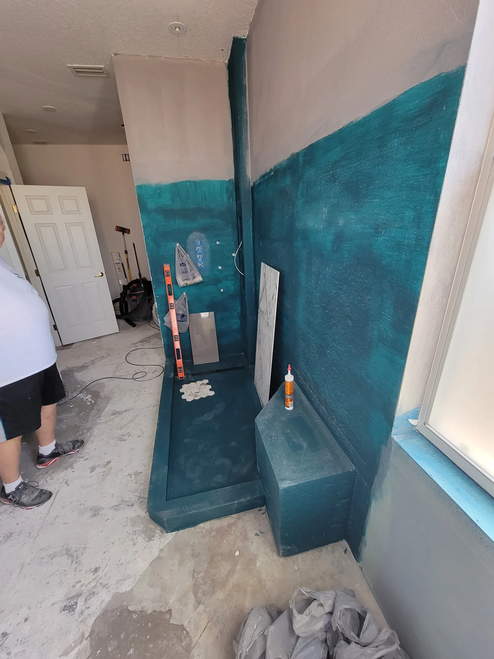 Shower bench and curb built and coated in teal waterproofing membrane