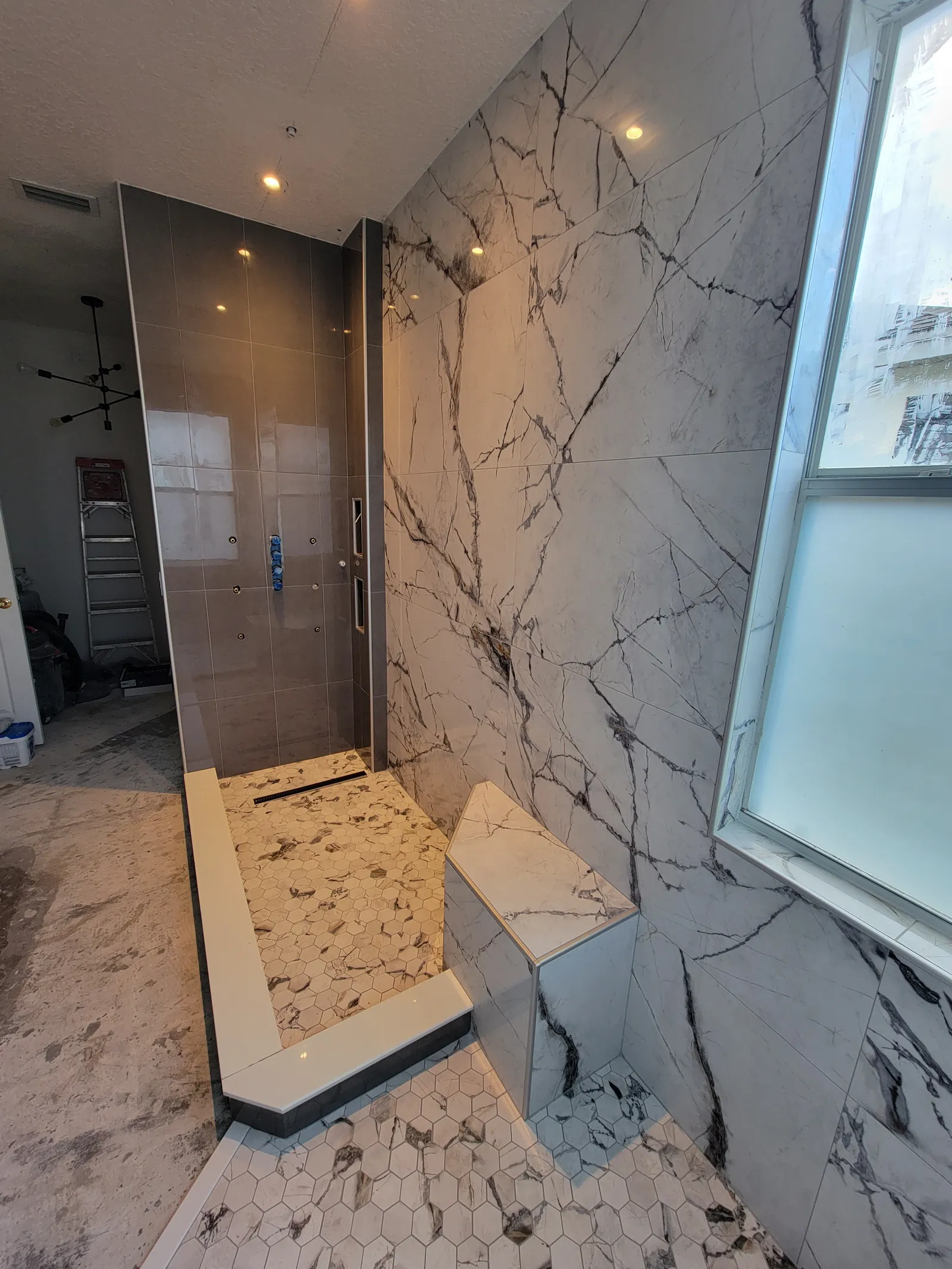 Finished shower with marble-look bench, window and hexagon mosaic floor