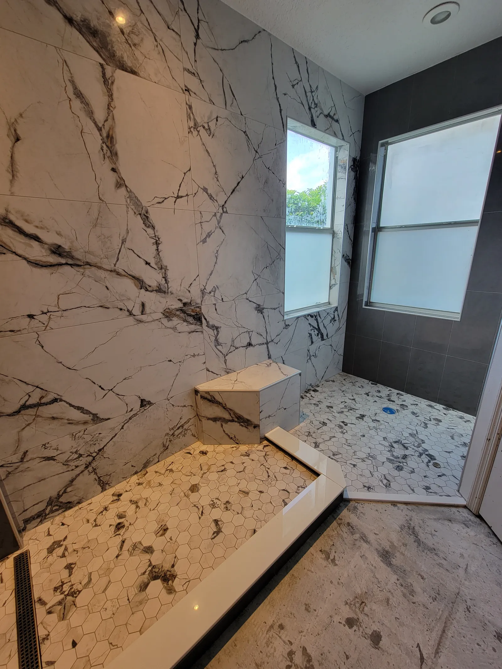 Finished shower with marble-look bench and hexagon mosaic floor