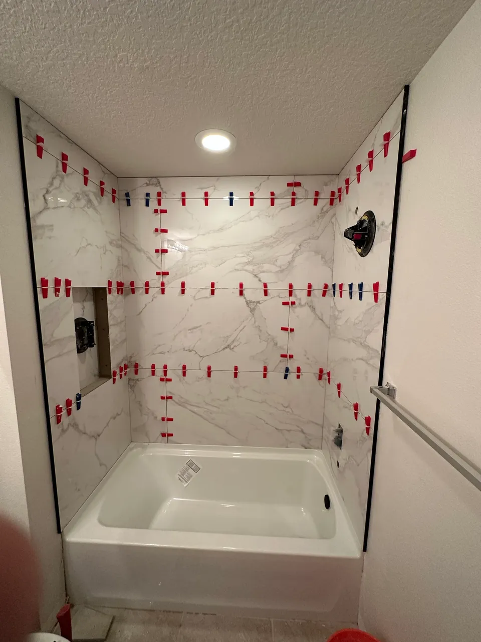 Large-format marble-look tile held flat with leveling clips during installation